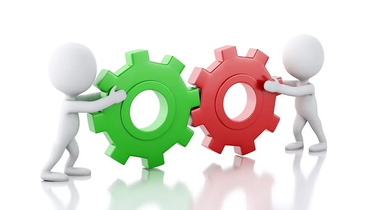 Two white figures work together to move a system of colored gears