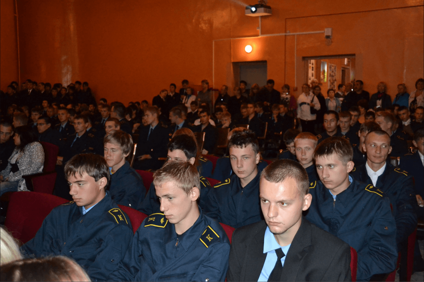 Cadets and guests seated in a crowded assembly hall.