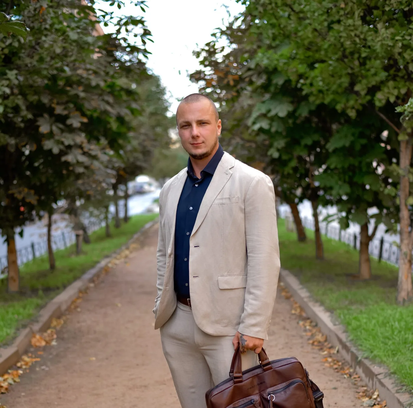 Anton Kolhonen in a light suit standing on a path among trees.