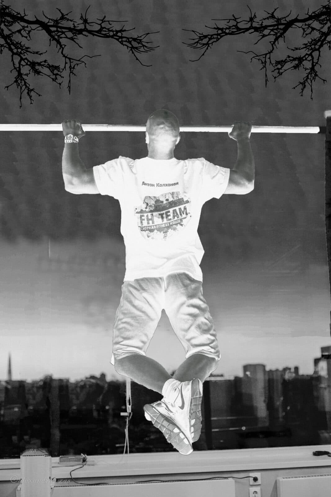 Anton Kolhonen, seen from behind, performs a pull-up at a large window.